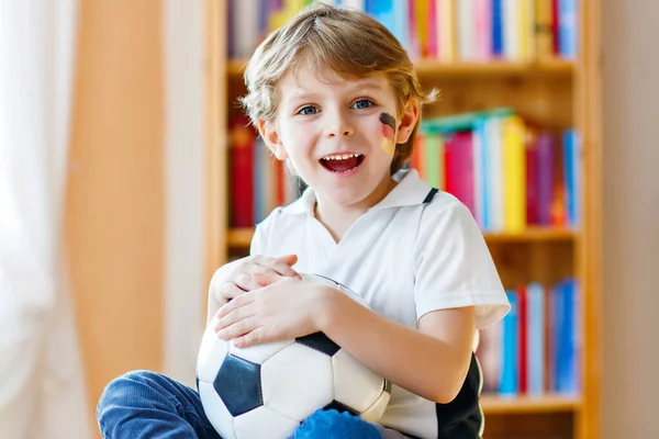 Pequeño niño rubio preescolar con bola viendo fútbol partido de la taza de fútbol en la televisión. —  Fotos de Stock