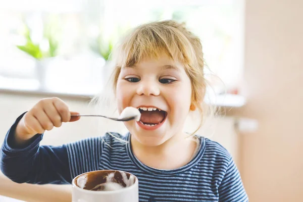 Adorabile bambina che beve latte caldo con schiuma. Felice bambino sano in casa, godendo bevanda al cioccolato. — Foto Stock