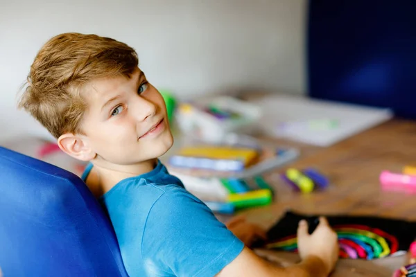 Piccolo ragazzo della scuola dipingere arcobaleno con diversi colori bastone su sfondo nero durante la malattia pandemica coronavirus quarantena. Bambini che dipingono arcobaleni in tutto il mondo. Felice bambino in casa — Foto Stock