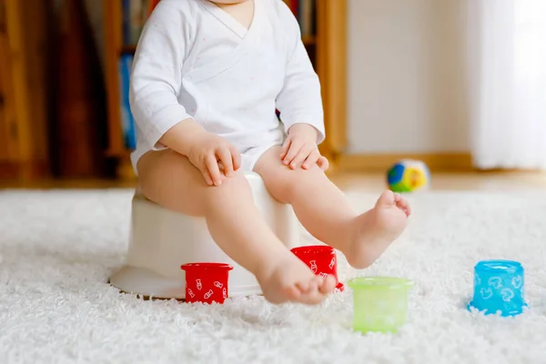 Close-up van schattige kleine peuter baby meisje kind zittend op het potje. Kid spelen met educatief speelgoed en toilet training concept. Baby leren, ontwikkelingsstappen. Geen gezicht, onherkenbaar persoon. — Stockfoto