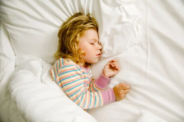 Söt liten småbarnstjej som sover i en stor säng med föräldrar. Bedårande barn drömmer i hotellsäng på familjesemester eller hemma. — Stockfoto