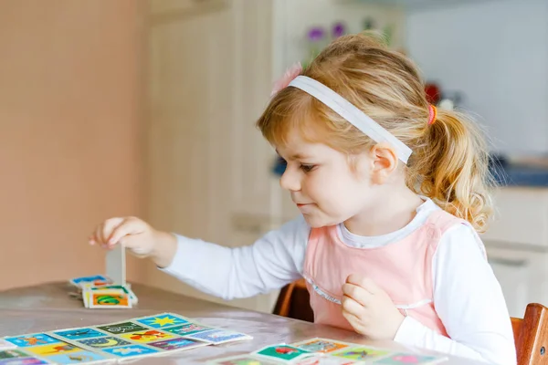 Schattige schattige peuter meisje spelen foto kaart spel. Gelukkige gezonde kind training geheugen, denken. Creatief binnen vrije tijd en onderwijs van het kind tijdens pandemische coronavirus covid quarantaine ziekte — Stockfoto