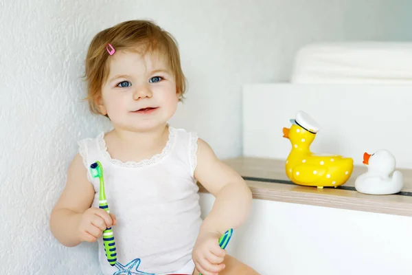 Niña sosteniendo cepillo de dientes y cepillándose los primeros dientes. Niños pequeños aprendiendo a limpiar los dientes de leche. — Foto de Stock