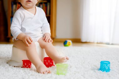 Lazımlığın üzerinde oturan küçük, tatlı, yaşlı, küçük kız bebek. Çocuk eğitim oyuncağı ve tuvalet eğitimi konseptiyle oynuyor. Bebek öğrenme, gelişme adımları. Yüzü yok, tanınmayan biri..