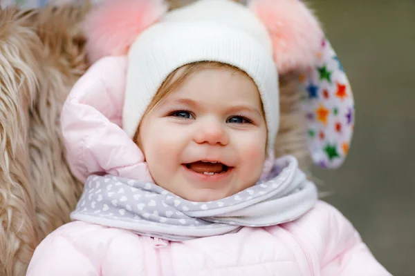 Linda niña hermosa sentada en el cochecito o cochecito en el frío otoño, invierno o día de primavera. Feliz niño sonriente en ropa de abrigo, abrigo de bebé con estilo de moda y sombrero. Nieve cayendo — Foto de Stock