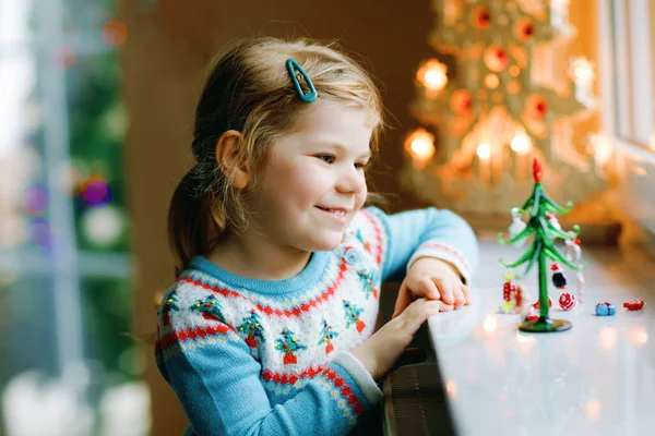 小女孩坐在窗边，用小的圣诞玩具装饰小玻璃杯圣诞树。健康快乐的孩子庆祝家人的传统节日.可爱的孩子. — 图库照片