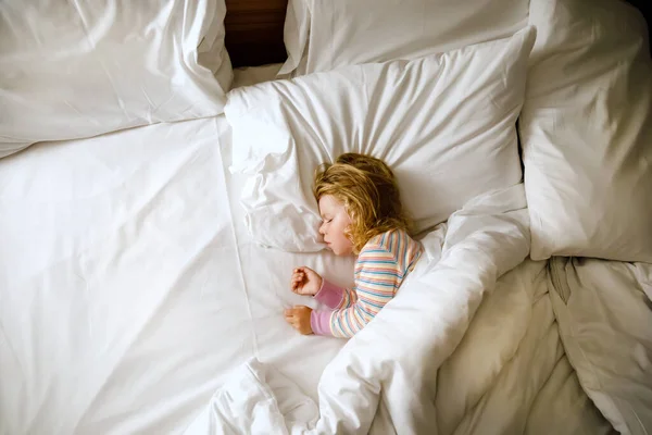 Cute little toddler girl sleeping in big bed of parents. Adorable baby child dreaming in hotel bed on family vacations or at home. — Stock Photo, Image
