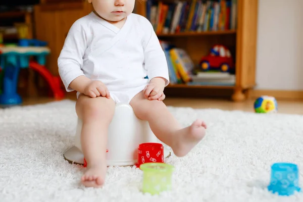Closeup of cute little old toddler baby girl child sitting on potty. Kid playing with educational toy and Toilet training concept. Baby learning, development steps. No face, unrecognizable person. — Stock Photo, Image