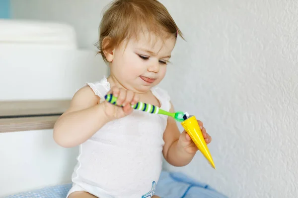 Niña sosteniendo cepillo de dientes y cepillándose los primeros dientes. Niño aprendiendo a limpiar los dientes de leche. Concepto de prevención, higiene y salud. Niño feliz en el baño — Foto de Stock