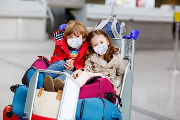 Duas crianças, rapaz e rapariga com máscaras médicas no aeroporto. Filhos felizes, família viajam juntos, vão de avião de férias. Pessoas em máscara como medida preventiva e proteção vívida. — Fotografia de Stock