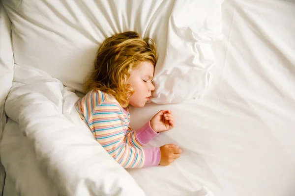 Söt liten småbarnstjej som sover i en stor säng med föräldrar. Bedårande barn drömmer i hotellsäng på familjesemester eller hemma. — Stockfoto