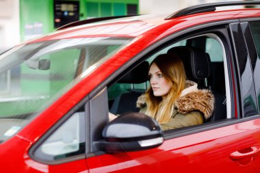 Mutlu, pozitif ifadeli, arabasıyla unutulmaz bir yolculukla tatmin olan genç ve çekici bir kadın sürücü koltuğunda oturuyor. İnsanlar, sürüş, ulaşım konsepti. Arabayla kış tatili