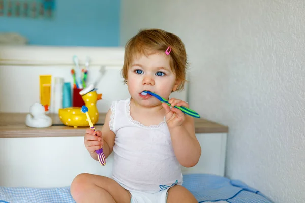 Mała dziewczynka trzymająca szczoteczkę i myjąca pierwsze zęby. Maluch uczy się czyścić zęby mleka. — Zdjęcie stockowe