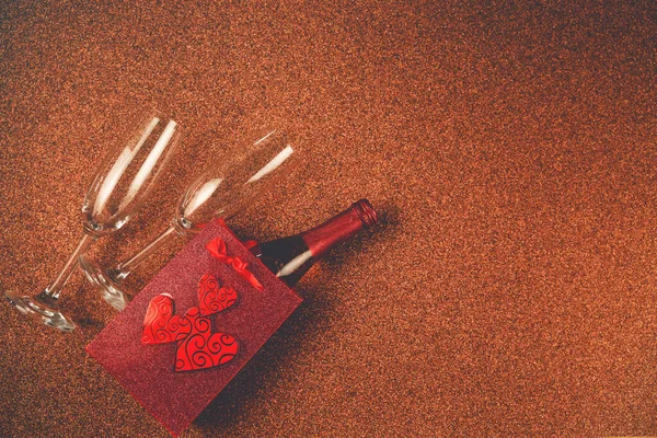 Gelukkige Valentijnsdag. Top view fles van rose champagne in geschenkdoos, harten, glazen op bruine glitter achtergrond. Valentijnsdag of Nieuwjaar wenskaart — Stockfoto