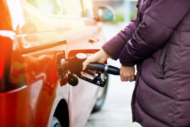 Benzin istasyonundaki kadına yakın çekim yapmak, yakıt hortumunu tutmak ve arabaya benzin, mazot ve benzin doldurmak. Otomobili benzin ya da benzinle doldur. Benzin pompası.