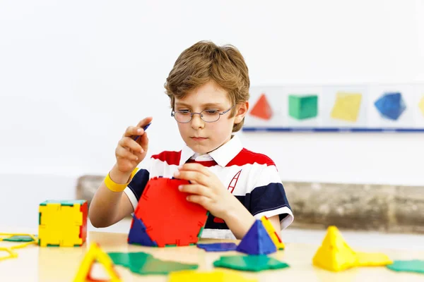 Menino feliz com óculos se divertindo com a construção e criação de figuras geométricas, aprendendo matemática e geometria — Fotografia de Stock