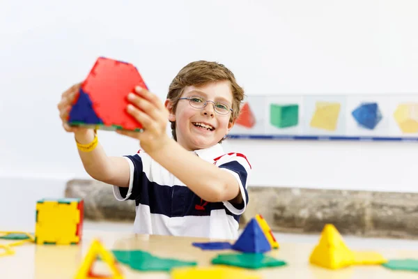 Menino feliz com óculos se divertindo com a construção e criação de figuras geométricas, aprendendo matemática e geometria — Fotografia de Stock