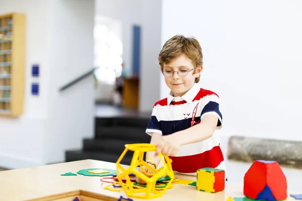 Glad pojke med glasögon som roar sig med att bygga och skapa geometriska figurer, lära sig matematik och geometri — Stockfoto