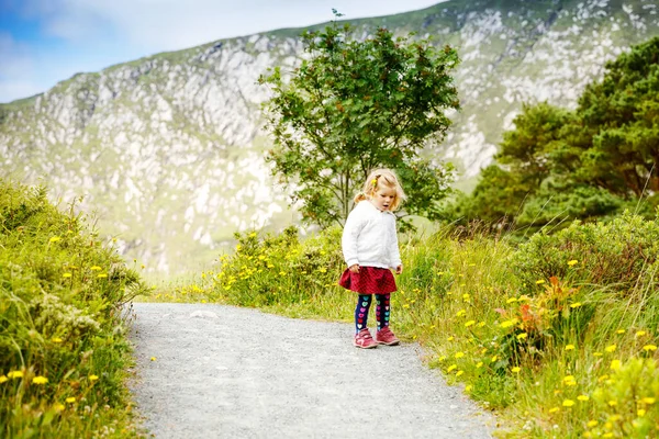 Roztomilé malé šťastné batole dívka běží na naučné stezce v Glenveagh národním parku v Irsku. Usmívající se a smějící se dítě baví trávení rodinných prázdnin v přírodě. Cestování s malými dětmi — Stock fotografie