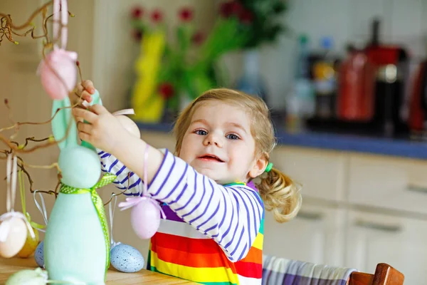 Carino piccolo bambino ragazza decorazione albero e coniglietto con uova di plastica pastello colorate. Bambino felice divertirsi con decorazioni pasquali. Adorabile bambino sorridente sano nel godersi la vacanza in famiglia — Foto Stock