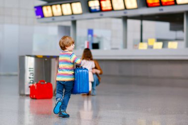 Uluslararası havaalanındaki terminalde büyük bavulları olan küçük mutlu çocuk. Okul öncesi heyecanlı çocuk uçuşu ve tatile çıkmayı bekliyor. Seyahat aile hayatı..