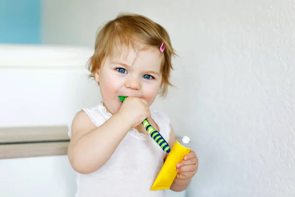 Niña sosteniendo cepillo de dientes y cepillándose los primeros dientes. Niño aprendiendo a limpiar los dientes de leche. Concepto de prevención, higiene y salud. Niño feliz en el baño — Foto de Stock