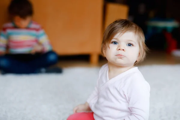 Evdeki sevimli kızın portresi. Küçük kız kameraya bakıyor ve gülümsüyor. Aile, yeni hayat, çocukluk, başlangıç konsepti. Kardeş çocuk arka planda. — Stok fotoğraf