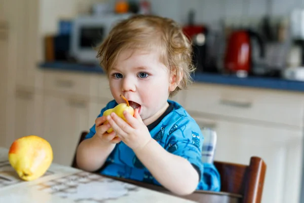 Linda adorable niña comiendo pera fresca. Bebé feliz hambriento de un año sosteniendo fruta. — Foto de Stock