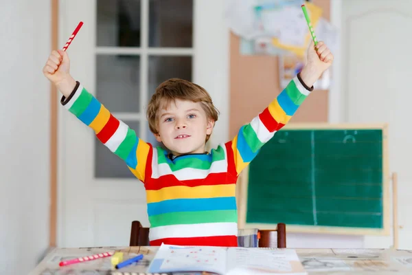 Retrato de menino da escola feliz bonito em casa fazendo lição de casa. Criança escrevendo com lápis coloridos, dentro de casa. Escola primária e educação. Criança pré-escolar aprendendo letras e números — Fotografia de Stock
