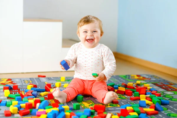 Чарівна дівчинка грає з освітніми іграшками. Щаслива здорова дитина розважається з різнокольоровими дерев'яними блоками вдома в домашній кімнаті. Дитячі кольори та форми навчання — стокове фото