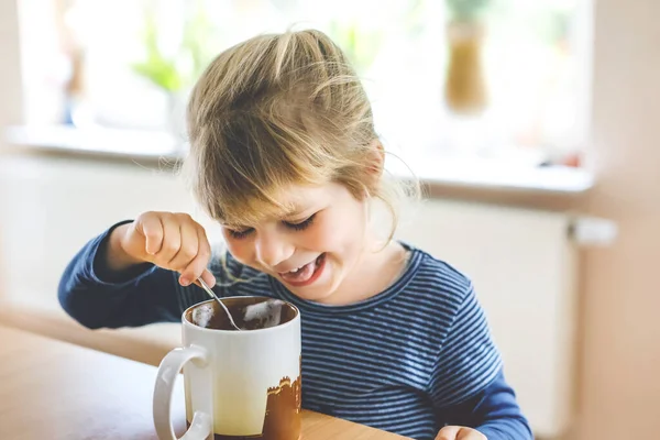 Menina adorável da criança bebendo leite quente com espuma. Criança saudável feliz dentro de casa, desfrutando de bebida de chocolate. — Fotografia de Stock