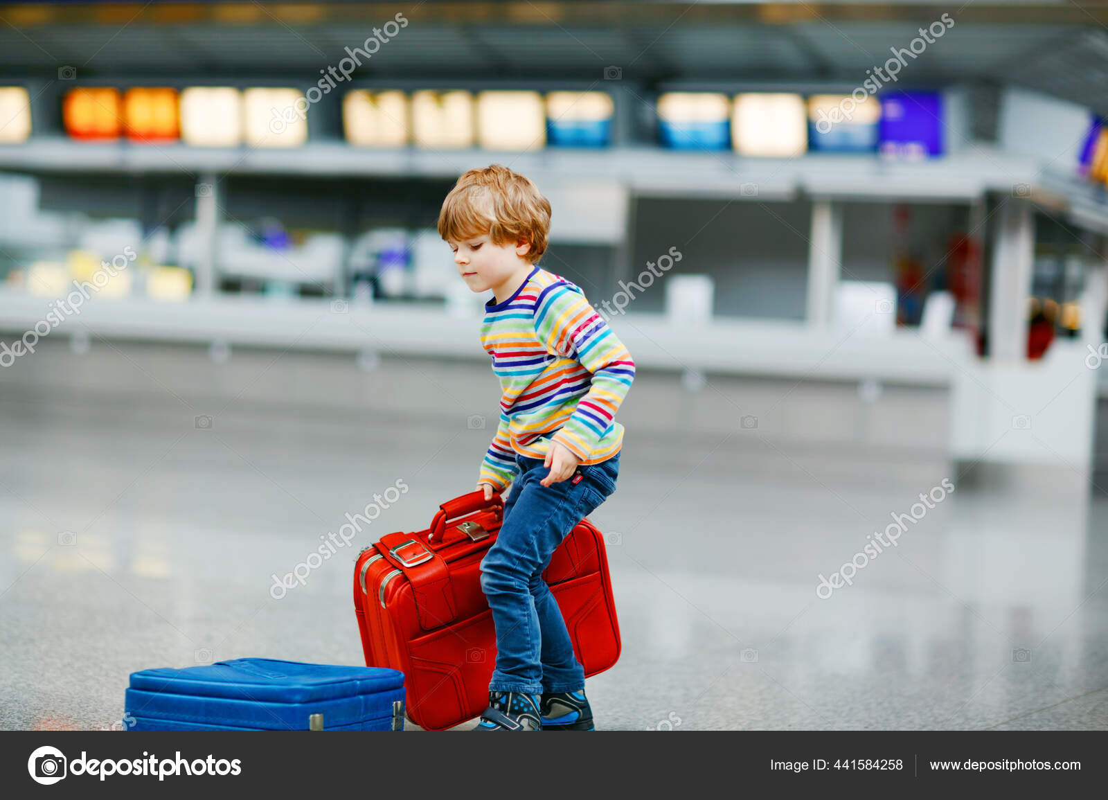 Happy little kid boy with big suitcase luggage at terminal on international airport. Preschool excited child wait for flight and going on vacations. Travel family lifestyle. Stock Photo romrodinka 441...