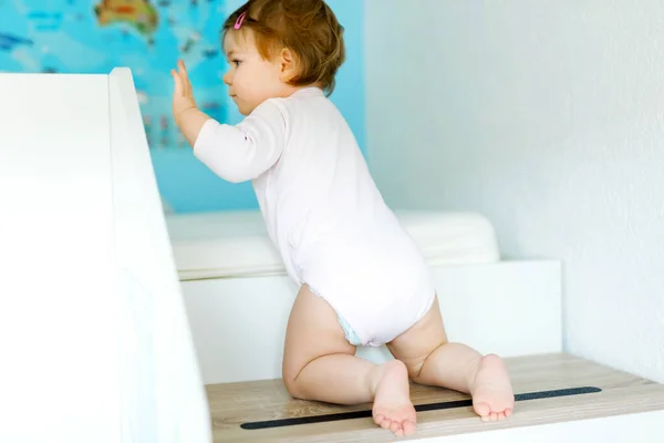 Niña aprendiendo a caminar, de pie y dando los primeros pasos en casa. Niño subiendo escaleras y equilibrándose. Niño feliz, equilibrio y desarrollo — Foto de Stock