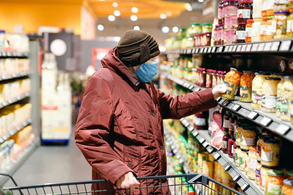 Oude oudere vrouw draagt een medisch masker, bescherming tegen pandemische coronavirus ziekte. 90 jaar gepensioneerde vrouwelijke dame duwen kar trolley om te winkelen in de supermarkt. Vrouw koopt eten en boodschappen — Stockfoto