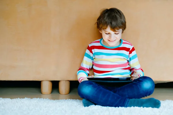 Um miúdo da escola a fazer trabalhos de casa com tablet. Leitura e aprendizagem escolar com computador, em busca de informações na internet. — Fotografia de Stock