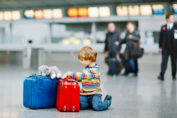 Niño feliz con un gran equipaje en la terminal del aeropuerto internacional. El niño preescolar emocionado espera el vuelo y se va de vacaciones. Viajes familia estilo de vida. — Foto de Stock