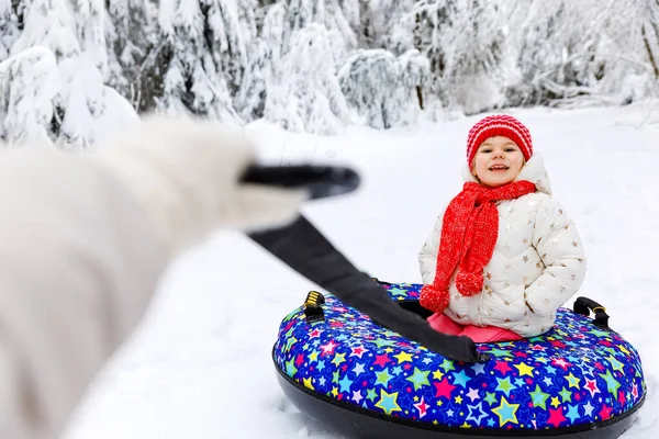 Mère tirer petite fille tout-petit sur le tube à neige. Mignon petit enfant heureux s'amuser à l'extérieur en hiver sur pneu coloré. Famille, fille et femme randonnée et marche dans la forêt enneigée, en plein air. — Photo