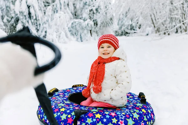 Mother pull little toddler girl on snow tube. Cute little happy child having fun outdoors in winter on colorful tire. Family, daughter and woman hiking and walking in snowy forest, outdoors. — Stock Photo, Image