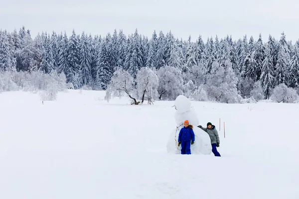 Två skolpojkar går i snöig vinterskog. Glada barn som har roligt utomhus på vintern. Familj, syskon och bröder vandrar och går tillsammans, utomhus. Aktiv fritid med barn — Stockfoto