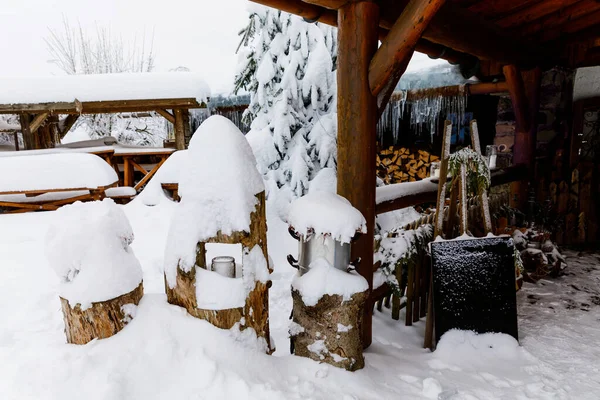 Restaurante al aire libre o cafetería con paisaje nevado en invierno, decorado con linternas de Navidad, luces e iluminación. Grandes carámbanos, nieve sobre abetos. — Foto de Stock