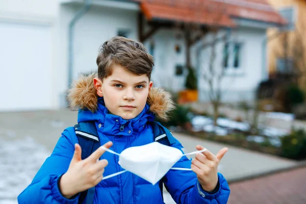 Kid boy wearing ffp medical mask on the way to school. Child backpack satchel. Schoolkid on cold autumn or winter day with warm clothes. Lockdown and quarantine time during corona pandemic disease — Stock Photo, Image