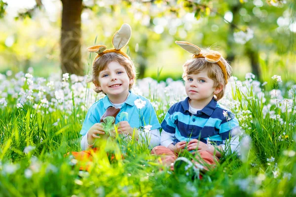 Due piccoli amici ragazzi a Pasqua orecchie di coniglio mangiare cioccolato — Foto Stock