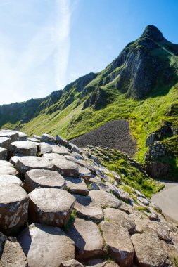Kuzey İrlanda, Antrim ilçesinde yaz mevsiminde mavi gökyüzü olan Giants Geçidi 'nin manzarası. UNESCO mirası. Eski bir volkanik yarığın sonucu olarak bazalt sütunların oluşturduğu bir alan.