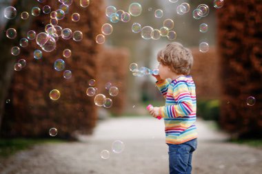 Preschool kid boy and little girl blowing on a dandelion flowers in park in the summer. Happy healthy toddler and school children with blowballs, having fun. Family of two love, together
