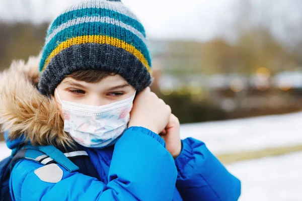 Kid boy wearing ffp medical mask on the way to school. Child backpack satchel. Schoolkid on cold autumn or winter day with warm clothes. Lockdown and quarantine time during corona pandemic disease — Stock Photo, Image