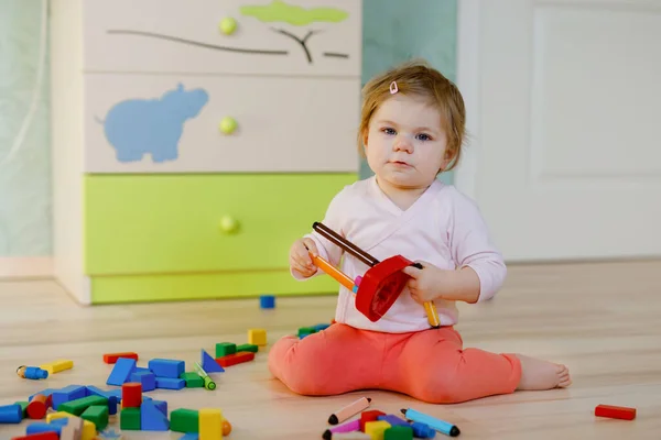 Eğitici oyuncaklarla oynayan tatlı küçük bir kız. Mutlu sağlıklı çocuk evde ya da çocuk odasında renkli tahta bloklarla eğleniyor. Bebek sürünüyor, renkleri ve biçimleri öğreniyor. — Stok fotoğraf