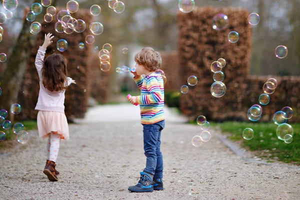 Preschool kid boy and little girl blowing on a dandelion flowers in park in the summer. Happy healthy toddler and school children with blowballs, having fun. Family of two love, together — Fotografia de Stock