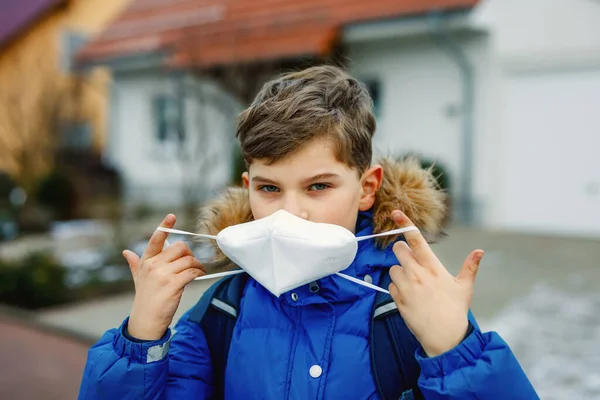 Kid boy wearing ffp medical mask on the way to school. Child backpack satchel. Schoolkid on cold autumn or winter day with warm clothes. Lockdown and quarantine time during corona pandemic disease — Stock Photo, Image