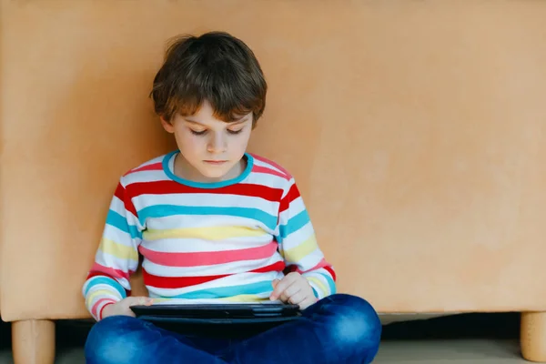 Little school kid boy making homework with tablet. Schoolchild reading and learning with computer, searching for information in internet. — Stock Photo, Image