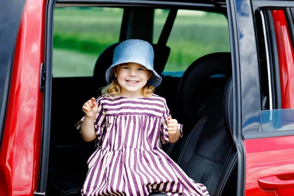 Adorable jeune fille assise dans un siège auto et regardant par la fenêtre sur la nature et la circulation. Petit enfant voyageant en voiture. Sécurité des enfants sur la route. Voyage en famille et vacances en été — Photo